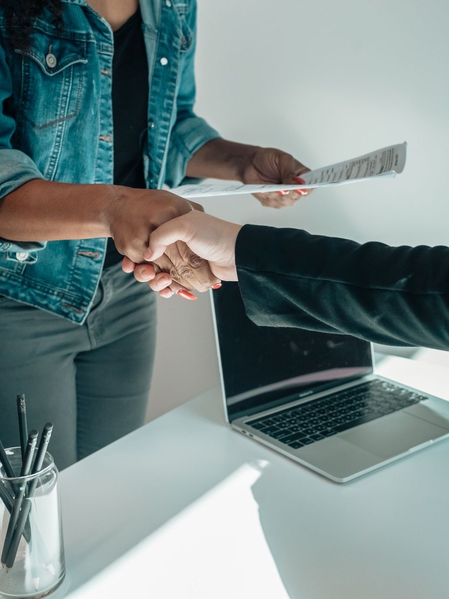 Deux personnes se serrant la main au-dessus d'un bureau, accord conclu