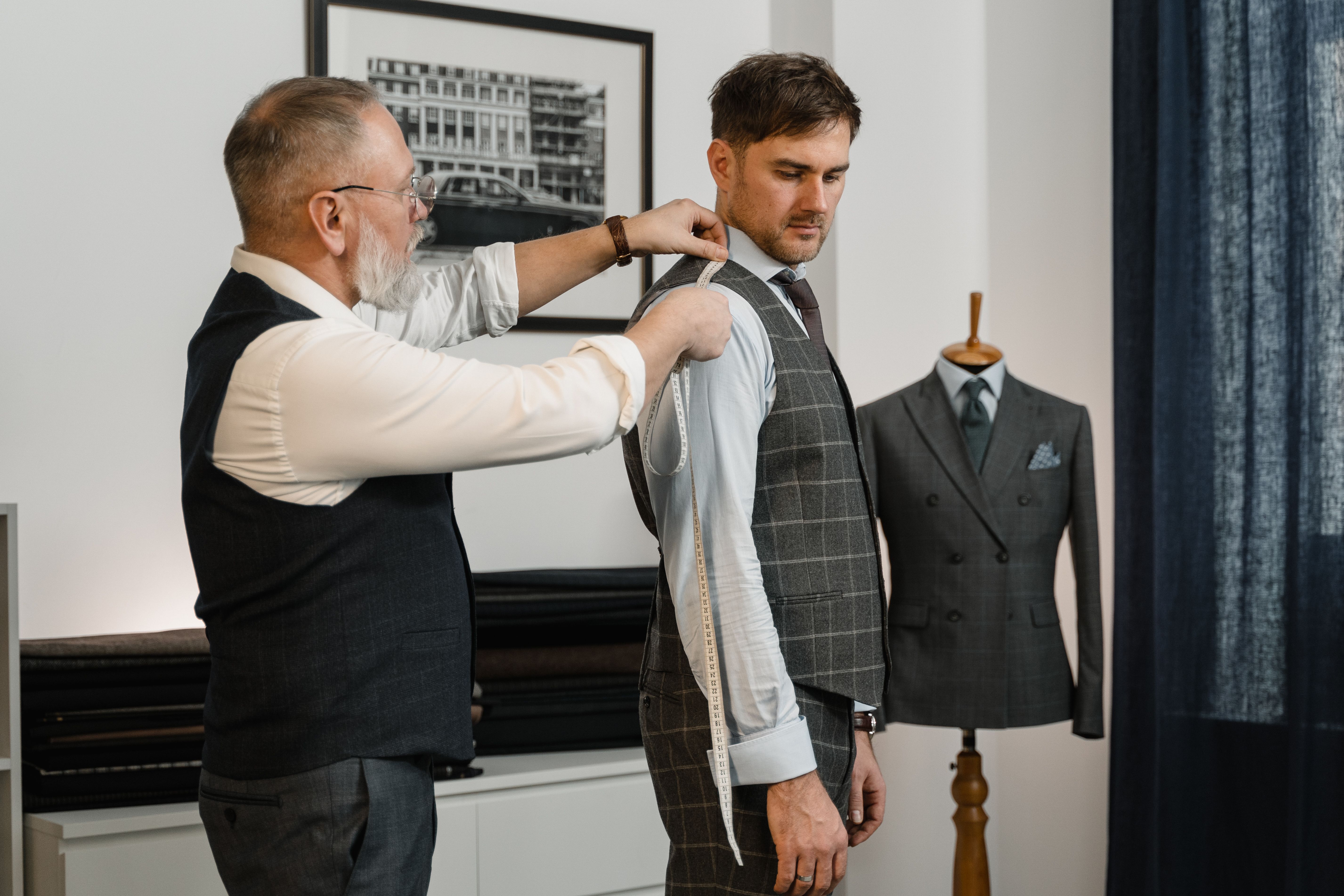 Tailleur prenant les mesures de son client avec un mètre-ruban