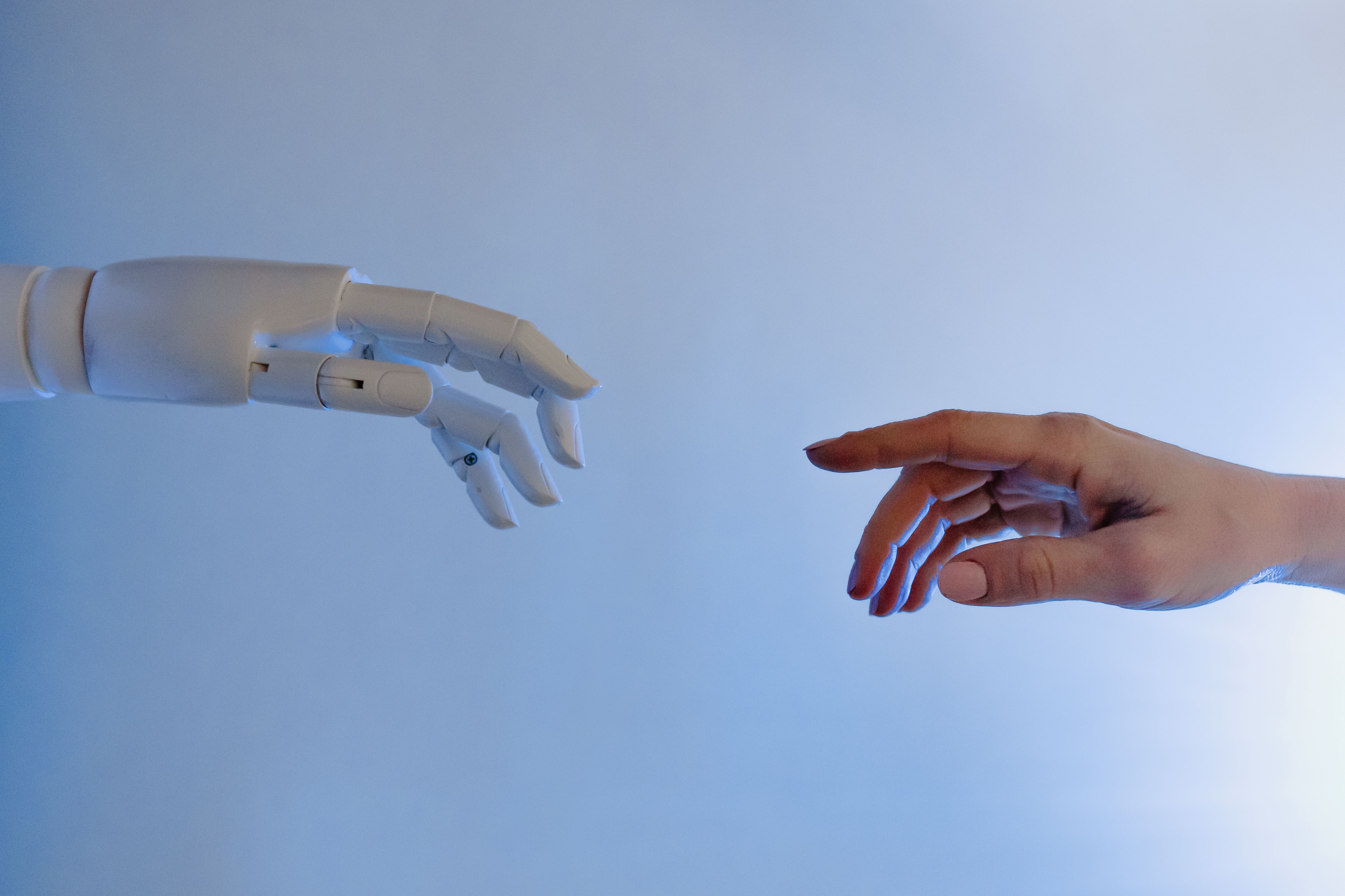 Une main humaine qui se tend vers une main robotique