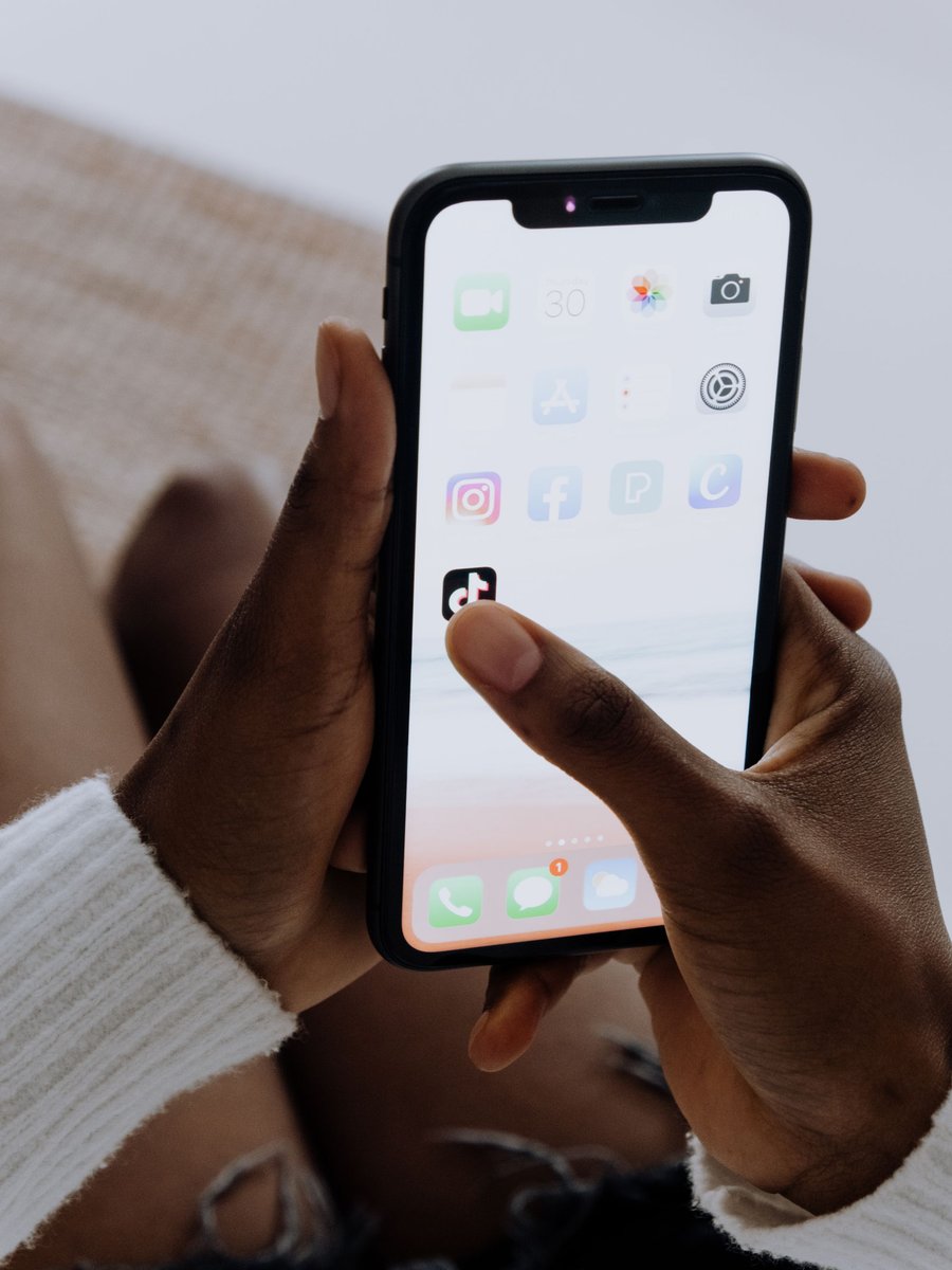 Mains tenant un téléphone affichant des applications de messagerie et de réseaux sociaux