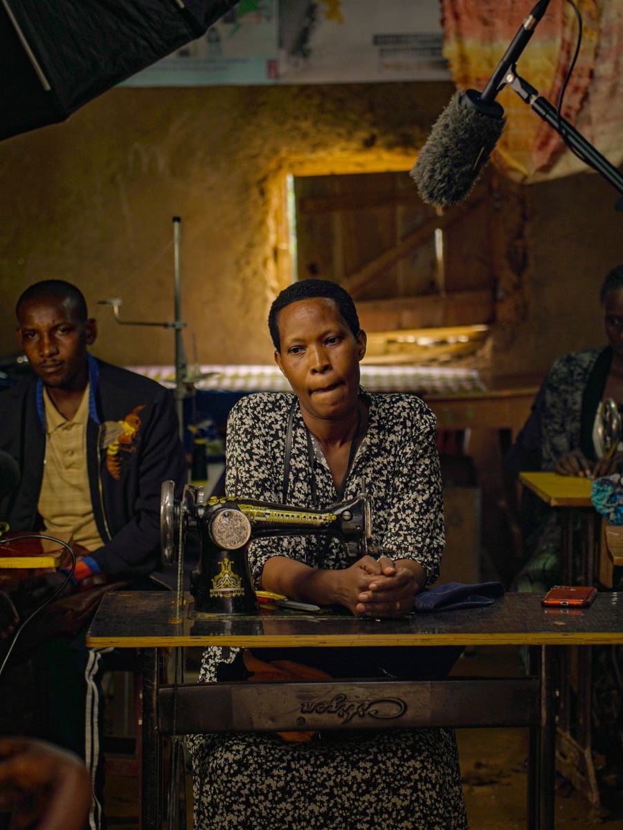 Atelier de couture africain : une couturière devant sa machine à manivelle, entourée d'apprentis
