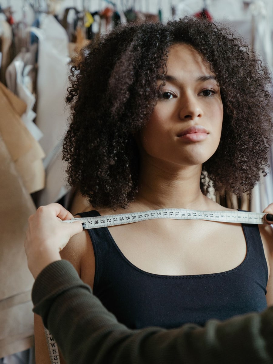 Couturière mesurant le tour de poitrine d'une cliente métisse avec un mètre ruban dans un atelier de couture
